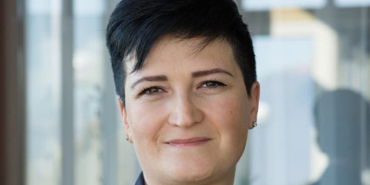 Portrait einer motivierten diplomierten Pflegefachfrau mit kurzen schwarzen Haaren.