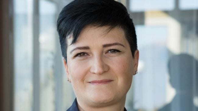 Portrait einer motivierten diplomierten Pflegefachfrau mit kurzen schwarzen Haaren.