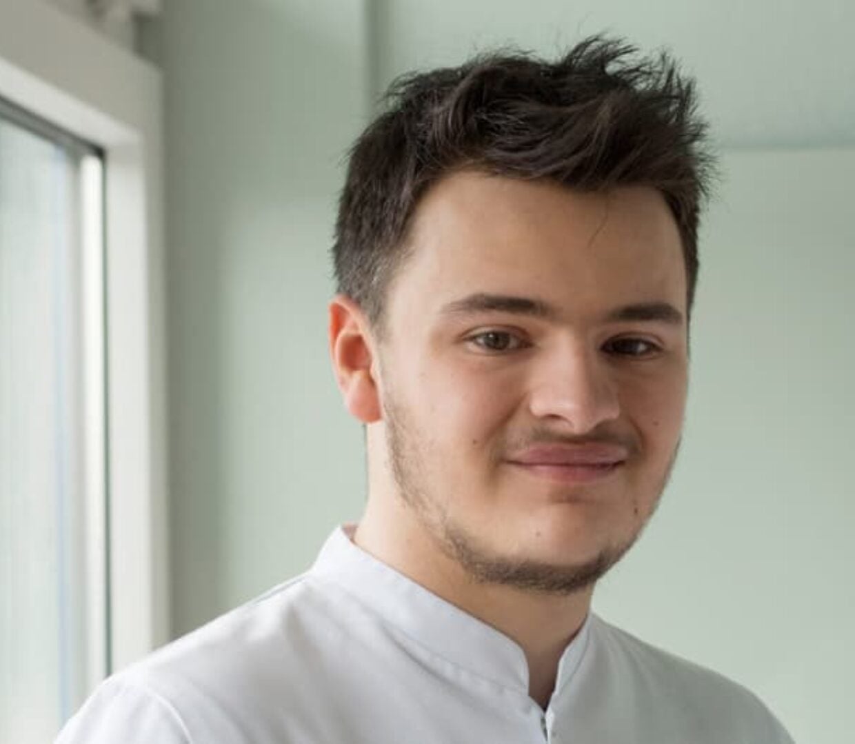 Portrait eines diplomierten Pflegefachmann in Ausbildung in Arbeitskleidung.