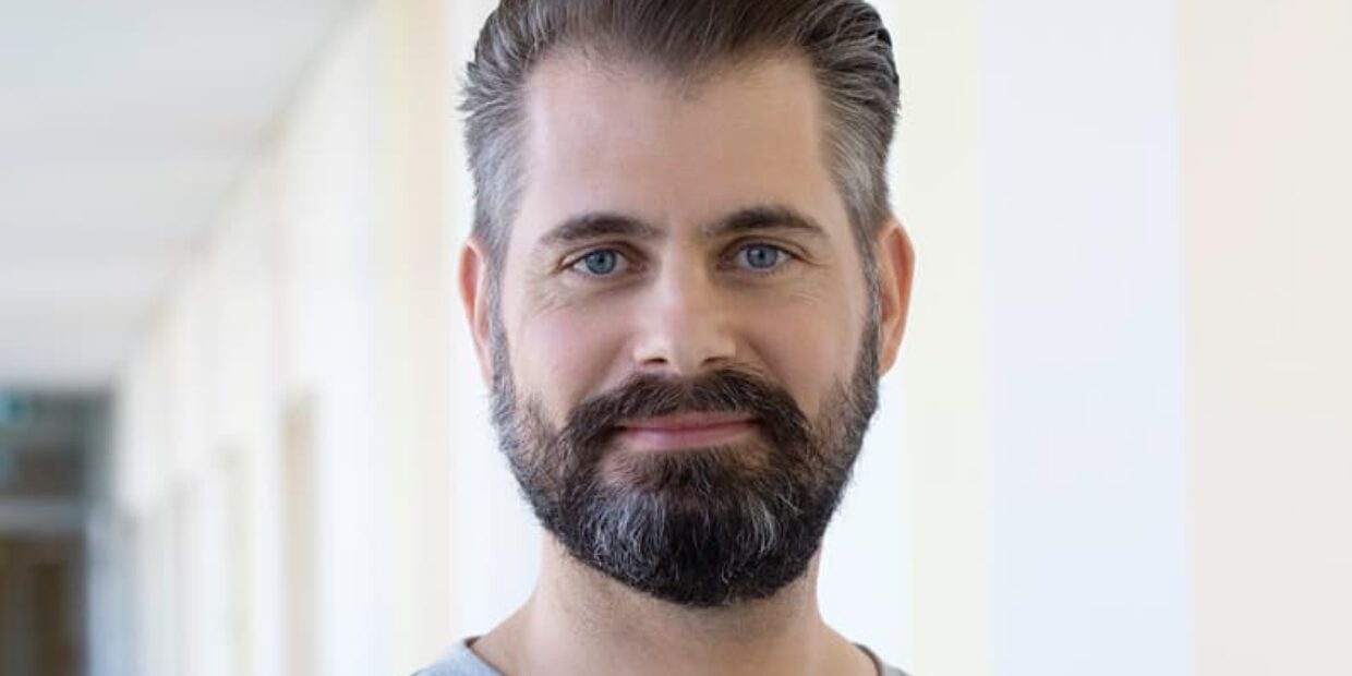 Portrait eines diplomierten Pflegefachmann HF mit Bart und blauen Augen.