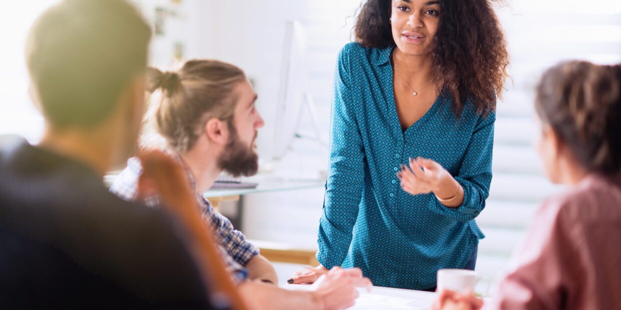 Meeting At Office. A Black Woman Talking With Her Colleagues
